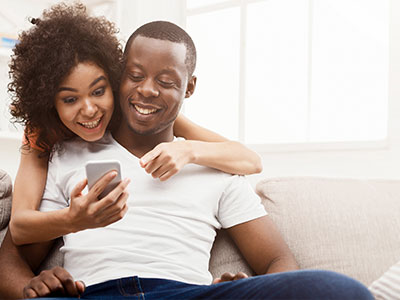 Young couple hugging looking at phone