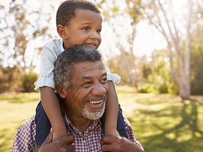 Grandfather with grandson on shoulders in park